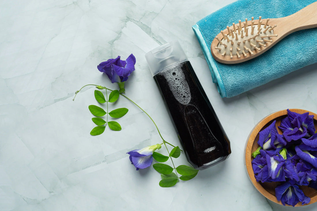 Which Shampoo Is Best For Hair: black shampoo bottle, wooden brush, flowers on marble surface.