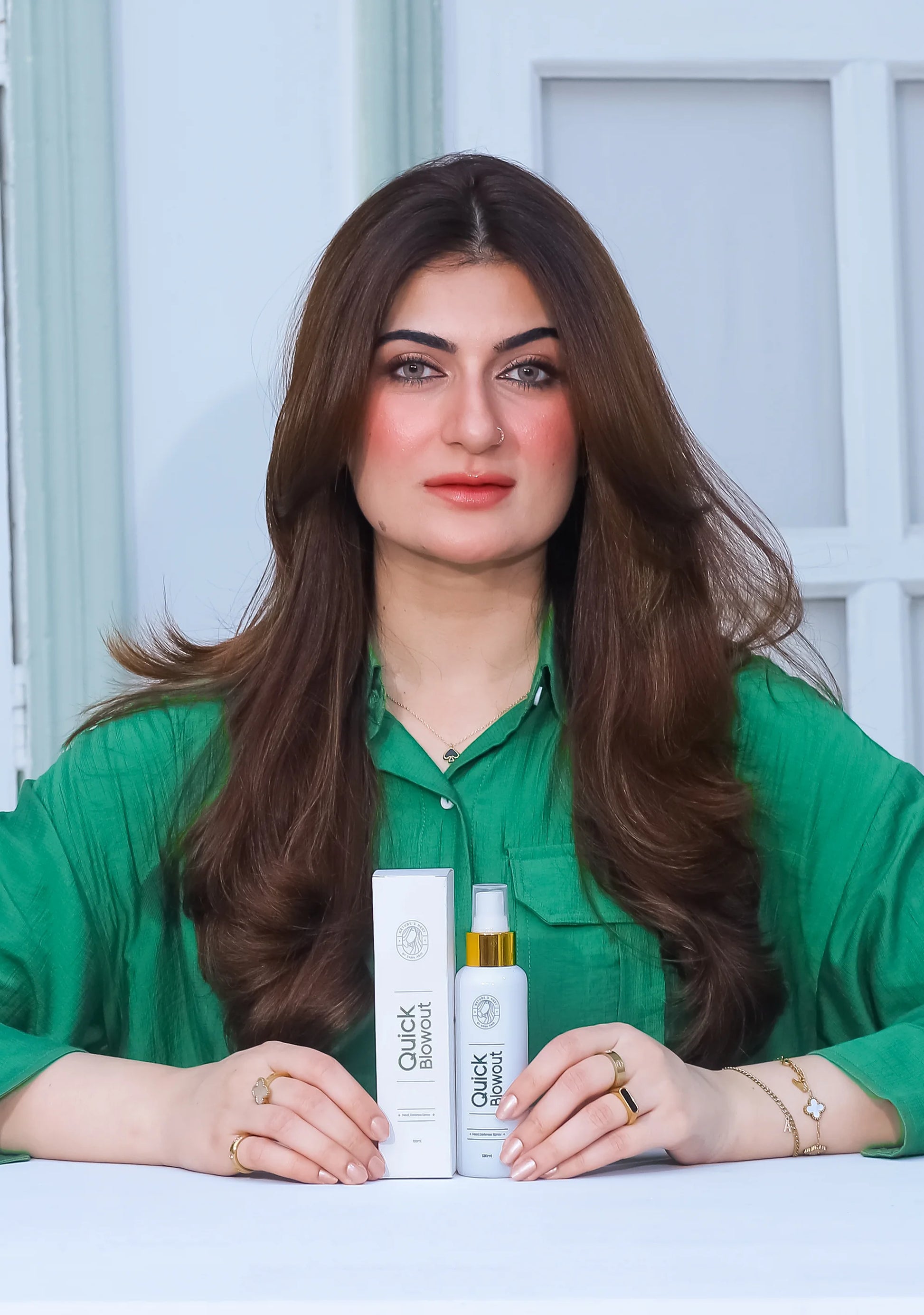 Model holding Quick Blowout Heat Defence Spray and its box, showcasing hair protection and styling benefits.