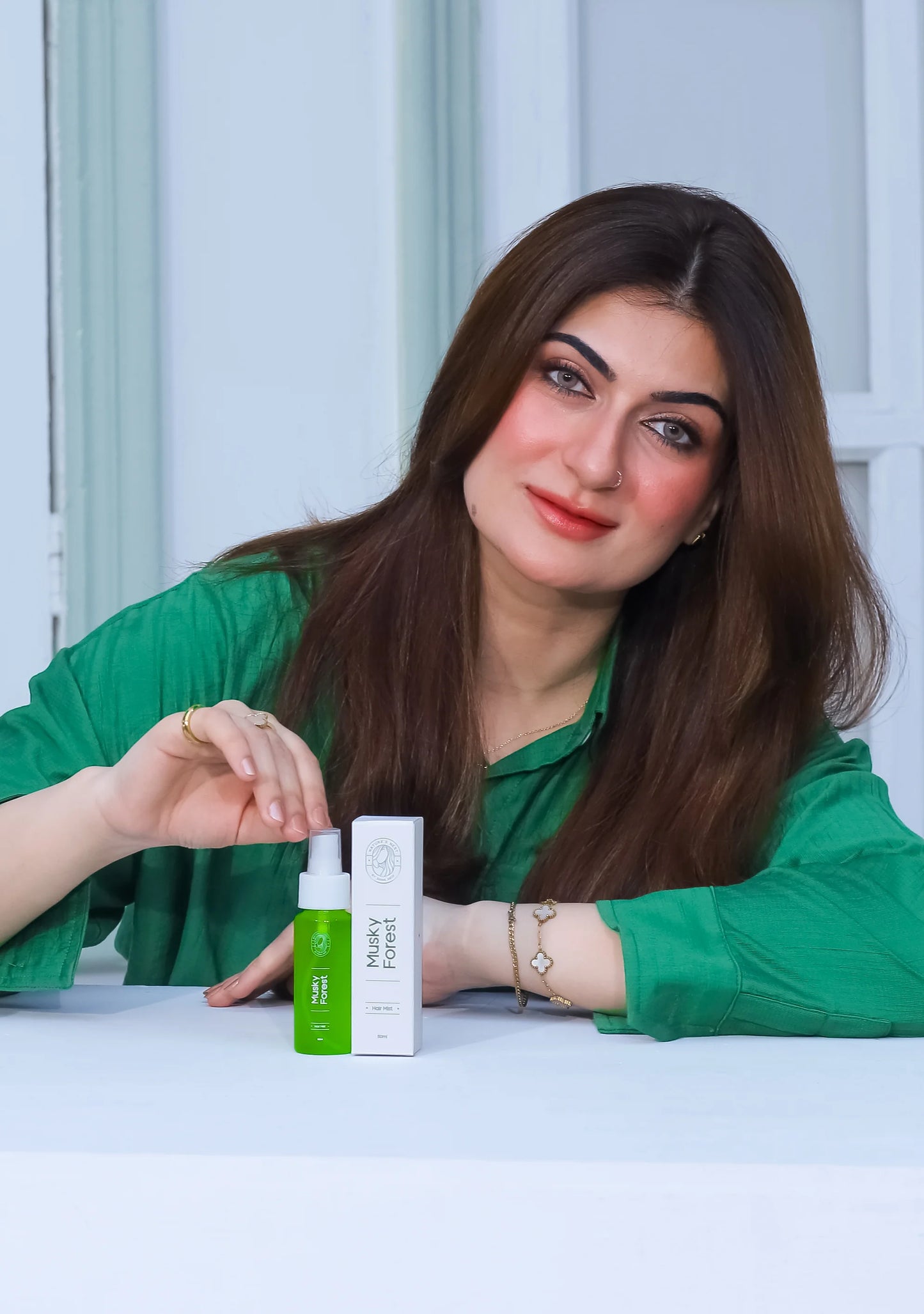 Sana Abid presenting MUSKY FOREST Hair Mist on a table, showcasing its luxury and natural essence.