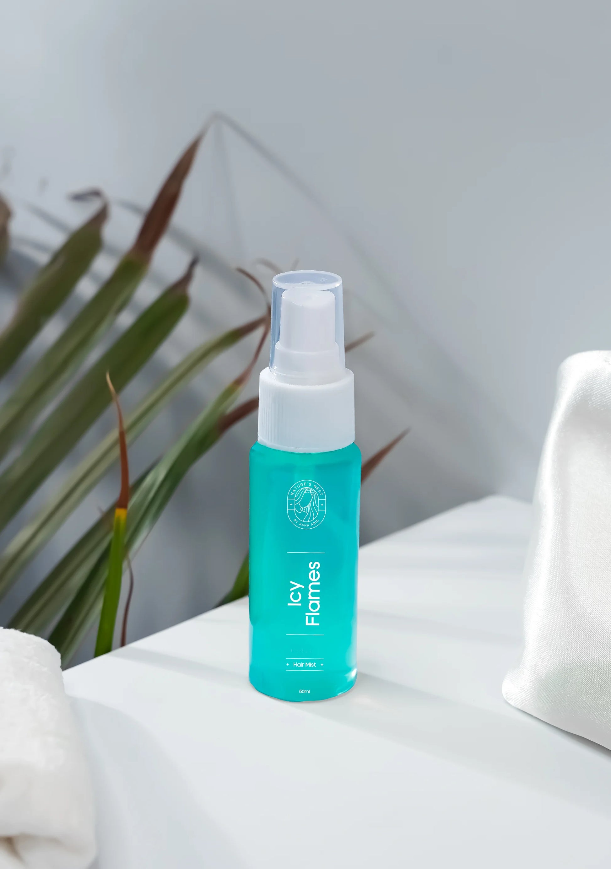 Icy Flames hair mist bottle on a clean surface with green plant leaves in the background.