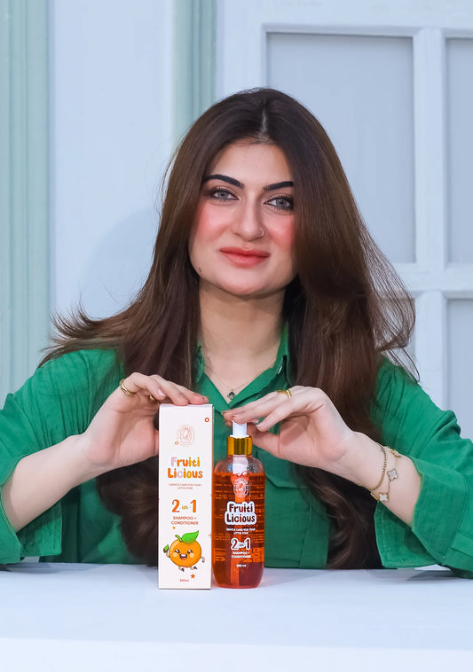 Woman promoting FRUITILICIOUS Tear Free Kids Shampoo and conditioner on a table.