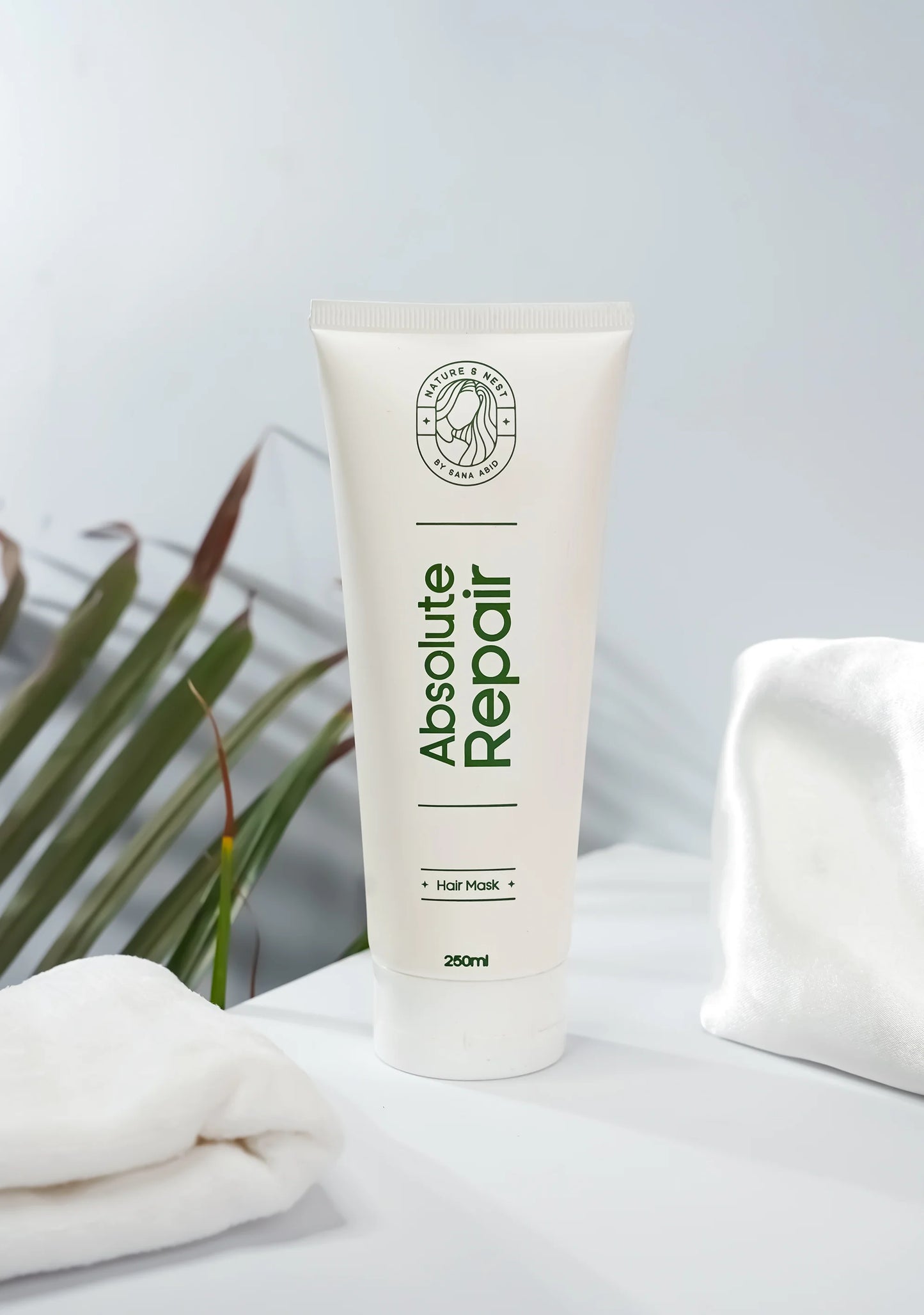 Absolute Repair Mask product packaging displayed with a soft towel and green plant background.