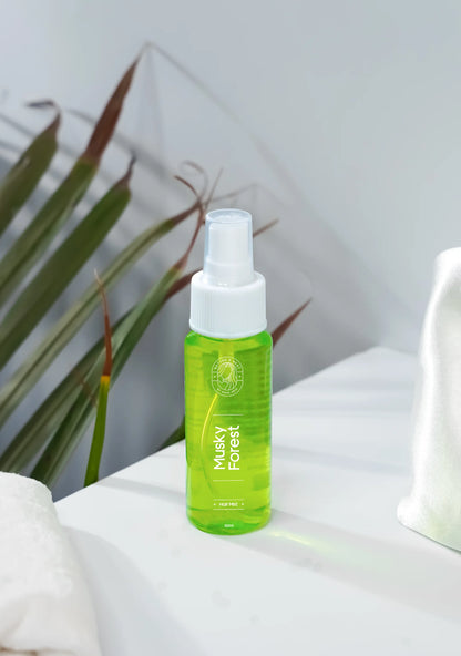 Musky Forest Hair Mist bottle on a white surface with green leaves in the background, promoting luxury hair care.